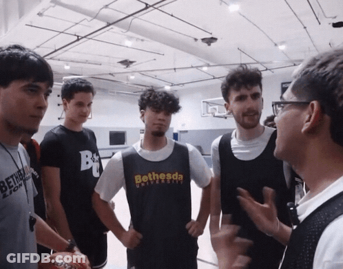 A Man Wearing A Bethesda University T-Shirt Talks To A Group Of Young Men GIF