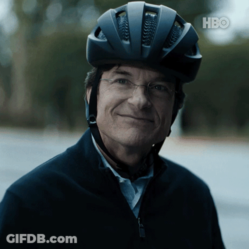 A Man Wearing A Bicycle Helmet And Glasses Is Smiling For The Camera With The Hbo Logo In The Background GIF