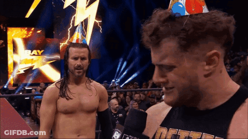 Man In Birthday Hat Talking To Another Man GIF