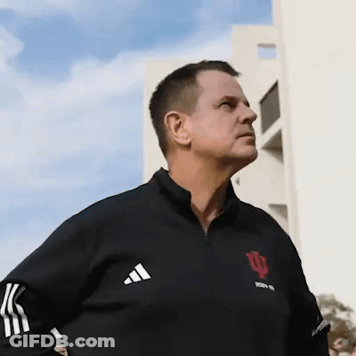 A Man Wearing A Black Adidas Jacket Stands In Front Of A White Building GIF