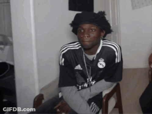 A Man Wearing A Black Adidas Shirt Is Sitting In A Chair GIF