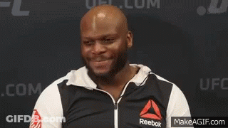 A Man Wearing A Black And White Reebok Jacket Is Standing In Front Of A Wall . GIF