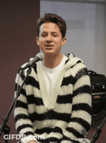 A Man Wearing A Black And White Striped Sweater Is Sitting In Front Of A Microphone GIF