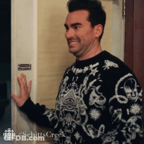 A Man Wearing A Black And White Sweater With The Word Schitts Creek On The Bottom GIF