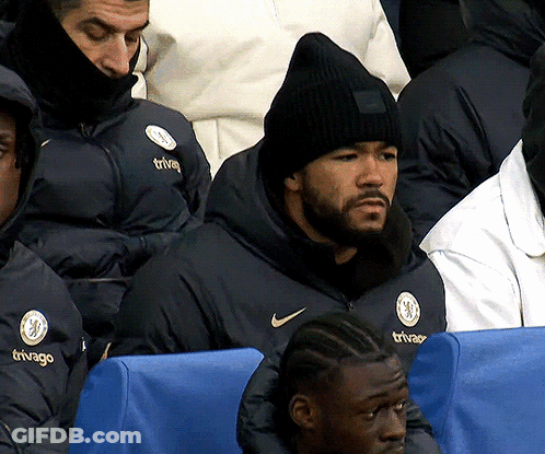A Man Wearing A Black Beanie Is Sitting In A Stadium Watching A Game GIF