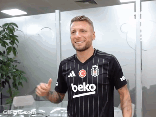 A Man Wearing A Black Beko Shirt Is Giving A Thumbs Up GIF