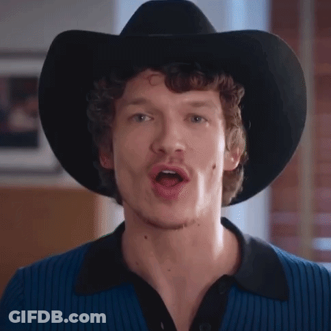 A Man Wearing A Black Cowboy Hat And A Blue Shirt Is Singing . GIF