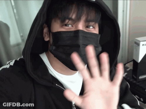 A Man Wearing A Black Face Mask And A Black Hoodie Is Waving GIF