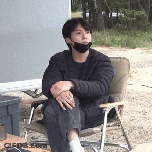 A Man Wearing A Black Face Mask Sits In A Chair GIF