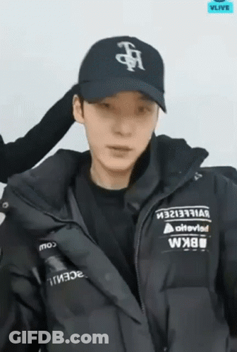 A Man Wearing A Black Hat And A Black Jacket Is Looking At The Camera . GIF