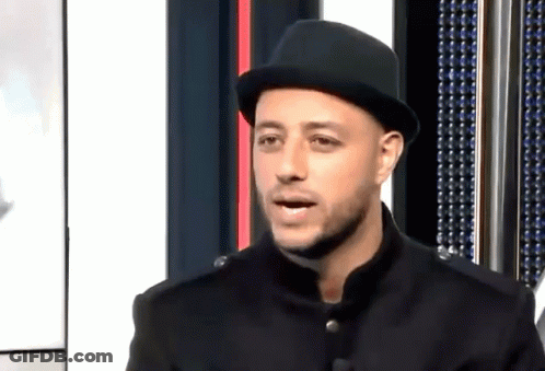 A Man Wearing A Black Hat And A Black Jacket Is Talking GIF