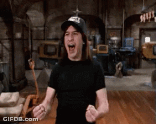 A Man Wearing A Black Hat And A Black Shirt Is Standing In A Room With His Arms In The Air . GIF