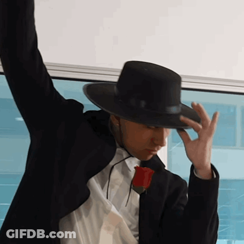 A Man Wearing A Black Hat And A Rose In His Pocket GIF