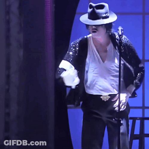 A Man Wearing A Black Hat And A White Shirt Is Standing In Front Of A Microphone GIF