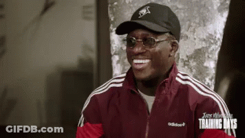 A Man Wearing A Black Hat And Sunglasses Is Smiling . GIF