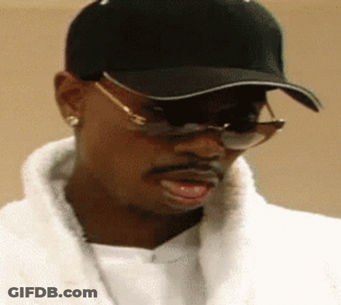 A Man Wearing A Black Hat And Sunglasses Looks To His Left GIF