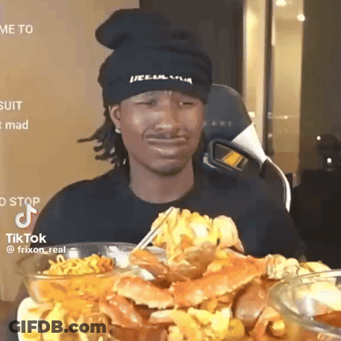 A Man Wearing A Black Hat Is Eating Crabs With Chopsticks .. GIF