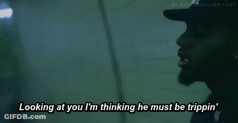 A Man Wearing A Black Hat Is Looking At Another Man While Talking . GIF
