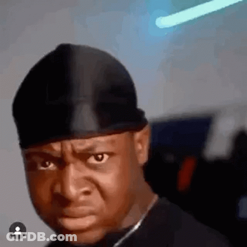 A Man Wearing A Black Hat Is Making A Funny Face And Looking At The Camera . GIF