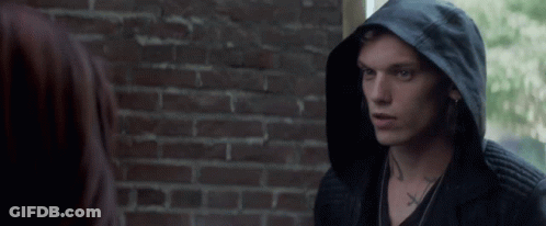 A Man Wearing A Black Hooded Jacket Has A Cross Tattoo On His Neck GIF