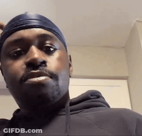 A Man Wearing A Black Hoodie And A Headband Looks At The Camera GIF