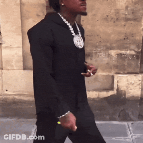 A Man Wearing A Black Hoodie And A Necklace With A Picture Of A Man On It GIF