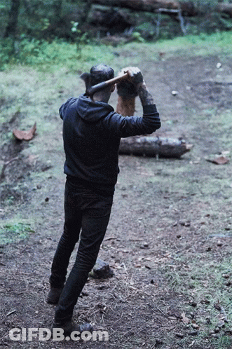 A Man Wearing A Black Hoodie Is Holding An Axe Over His Head GIF