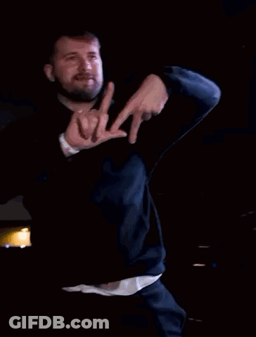 A Man Wearing A Black Hoodie Is Making A Hand Gesture With His Fingers GIF