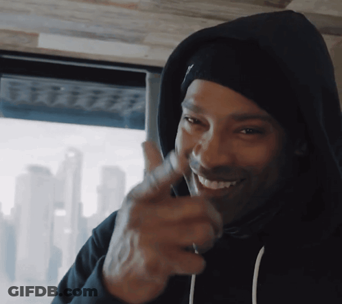 A Man Wearing A Black Hoodie Is Smiling And Pointing His Finger GIF