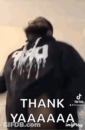 A Man Wearing A Black Hoodie With The Words `` Thank Yaaaa '' On The Back Is Dancing . GIF