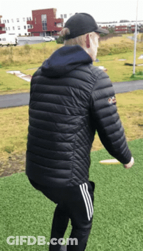 A Man Wearing A Black Jacket And A Black Hat Is Squatting Down GIF