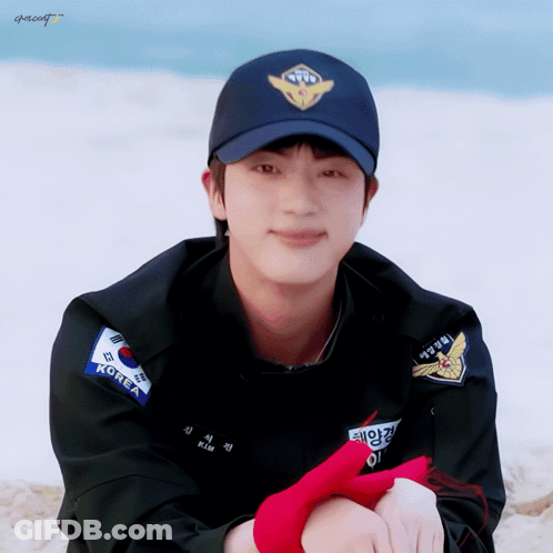 A Man Wearing A Black Jacket And A Blue Hat With The Word Korea On It GIF