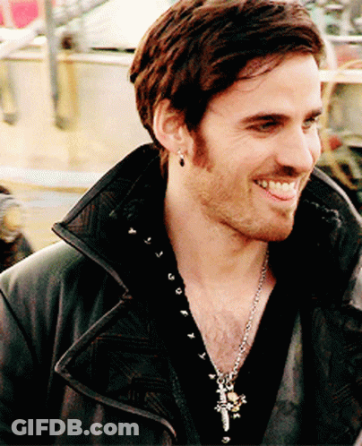 A Man Wearing A Black Jacket And A Cross Necklace Smiles For The Camera GIF