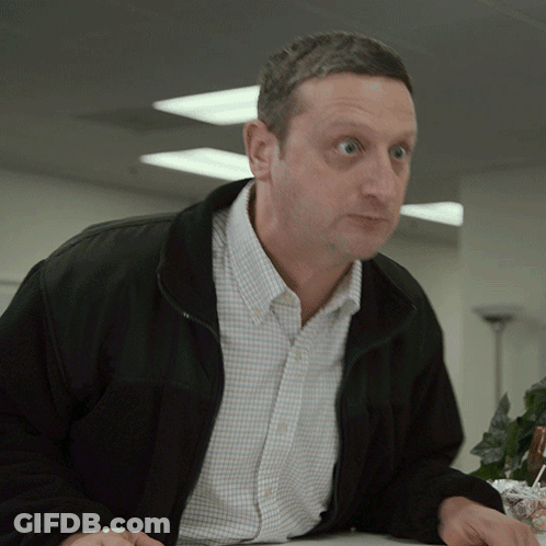 A Man Wearing A Black Jacket And A Plaid Shirt Looks At Something GIF
