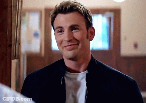 A Man Wearing A Black Jacket And A White Shirt Is Smiling In A Room . GIF