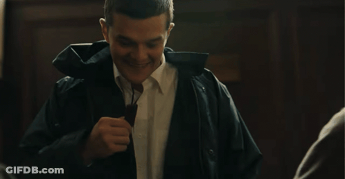 A Man Wearing A Black Jacket And A White Shirt Laughs GIF