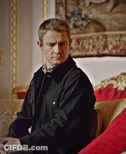 A Man Wearing A Black Jacket Sits On A Couch GIF