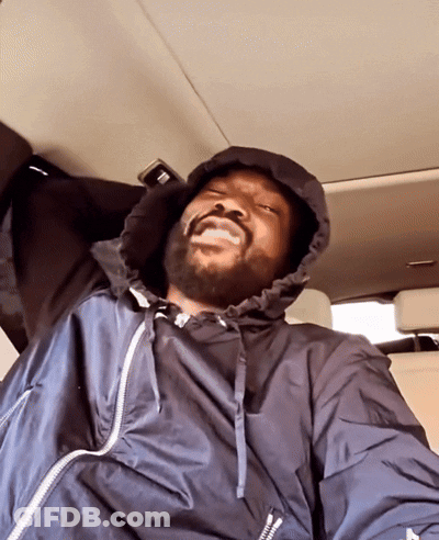 A Man Wearing A Black Jacket With A White Zipper Is Sitting In The Back Seat Of A Car GIF