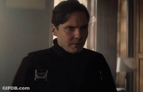A Man Wearing A Black Jacket With The Letter K On It Looks At The Camera GIF