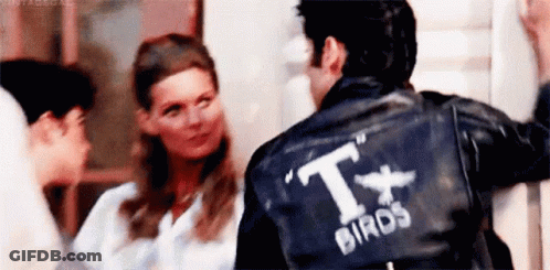 A Man Wearing A Black Leather Jacket With The Word Birds On The Back Is Standing Next To A Woman . GIF
