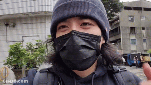 A Man Wearing A Black Mask And A Beanie Is Looking At The Camera GIF