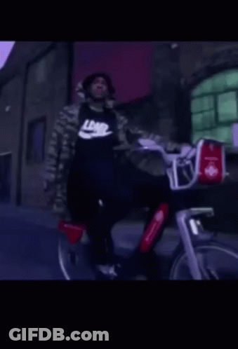 A Man Wearing A Black Nike Shirt Rides A Bike GIF
