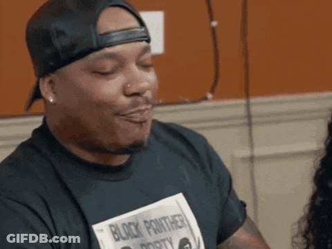 A Man Wearing A Black Panther Shirt Is Making A Face GIF