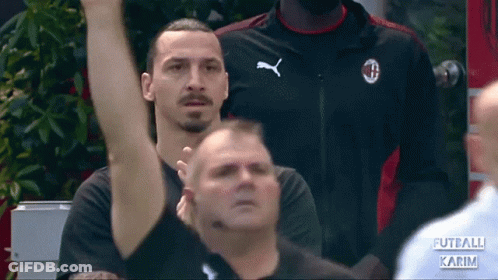 A Man Wearing A Black Puma Shirt Stands In A Crowd GIF