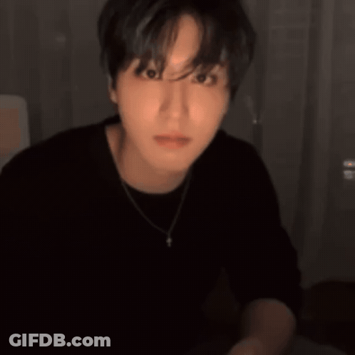 A Man Wearing A Black Shirt And A Necklace Is Smiling And Pointing GIF