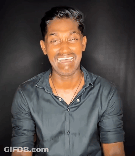 A Man Wearing A Black Shirt And A Necklace Smiles For The Camera GIF