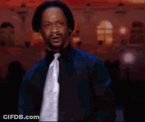 A Man Wearing A Black Shirt And Tie Is Standing In Front Of A Building GIF