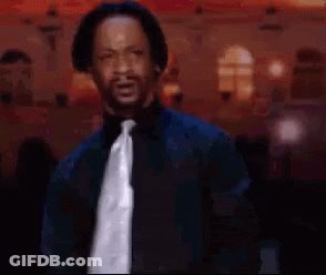 A Man Wearing A Black Shirt And Tie Is Standing In Front Of A Crowd . GIF