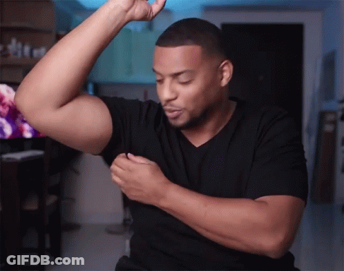 A Man Wearing A Black Shirt Is Flexing His Muscles GIF