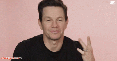 A Man Wearing A Black Shirt Is Giving A Peace Sign In Front Of An Esquire Logo GIF
